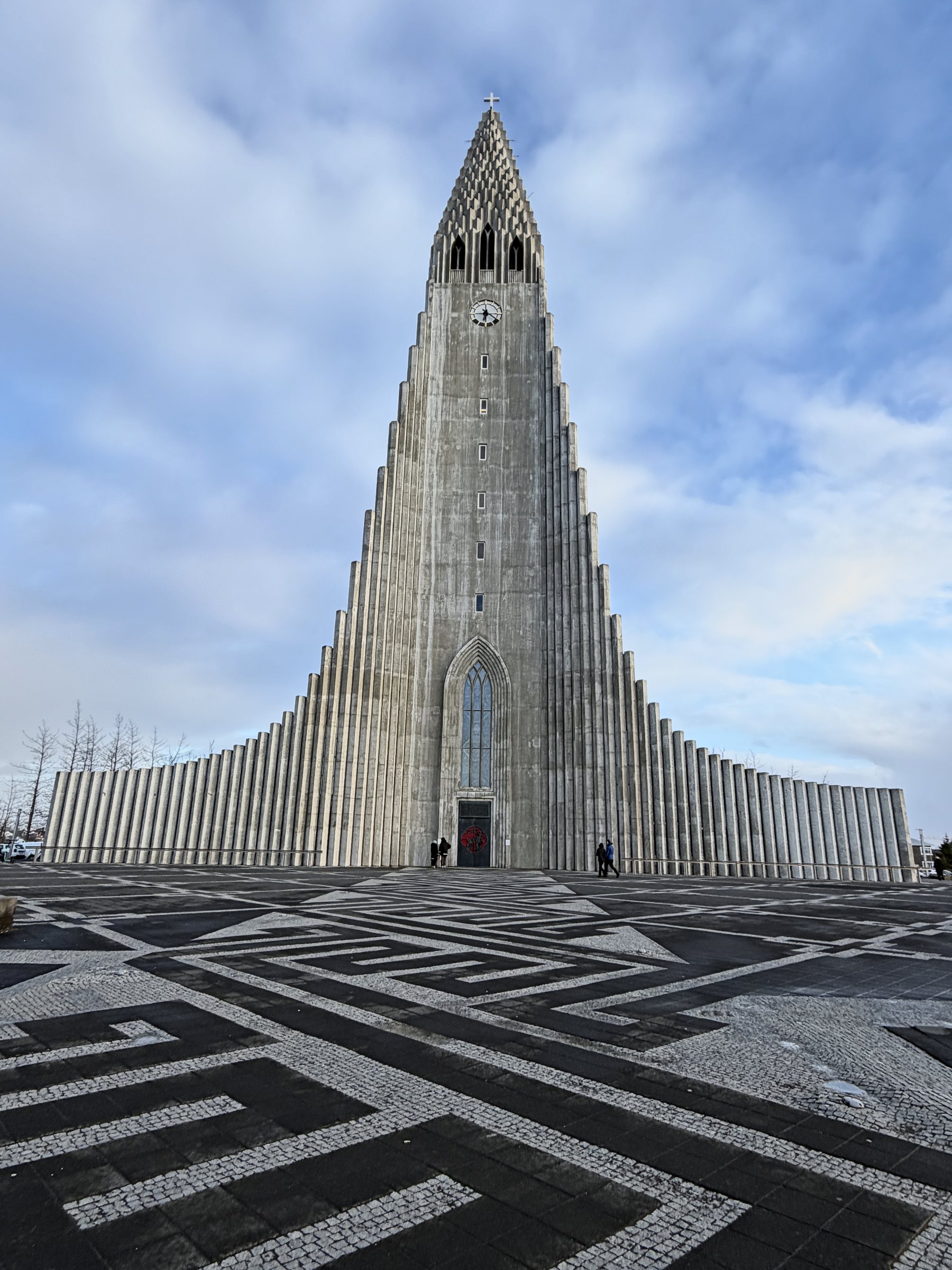 Hallgrímskirkja church, its stepped concrete columns rising to a spire, above a patterned black-and-white plaza.