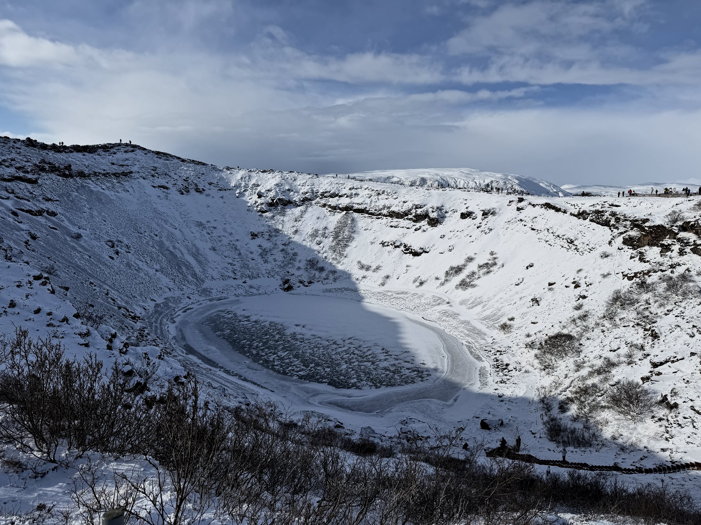 The snow-covered rim of Kerið crater, its lake frozen white at the bottom.