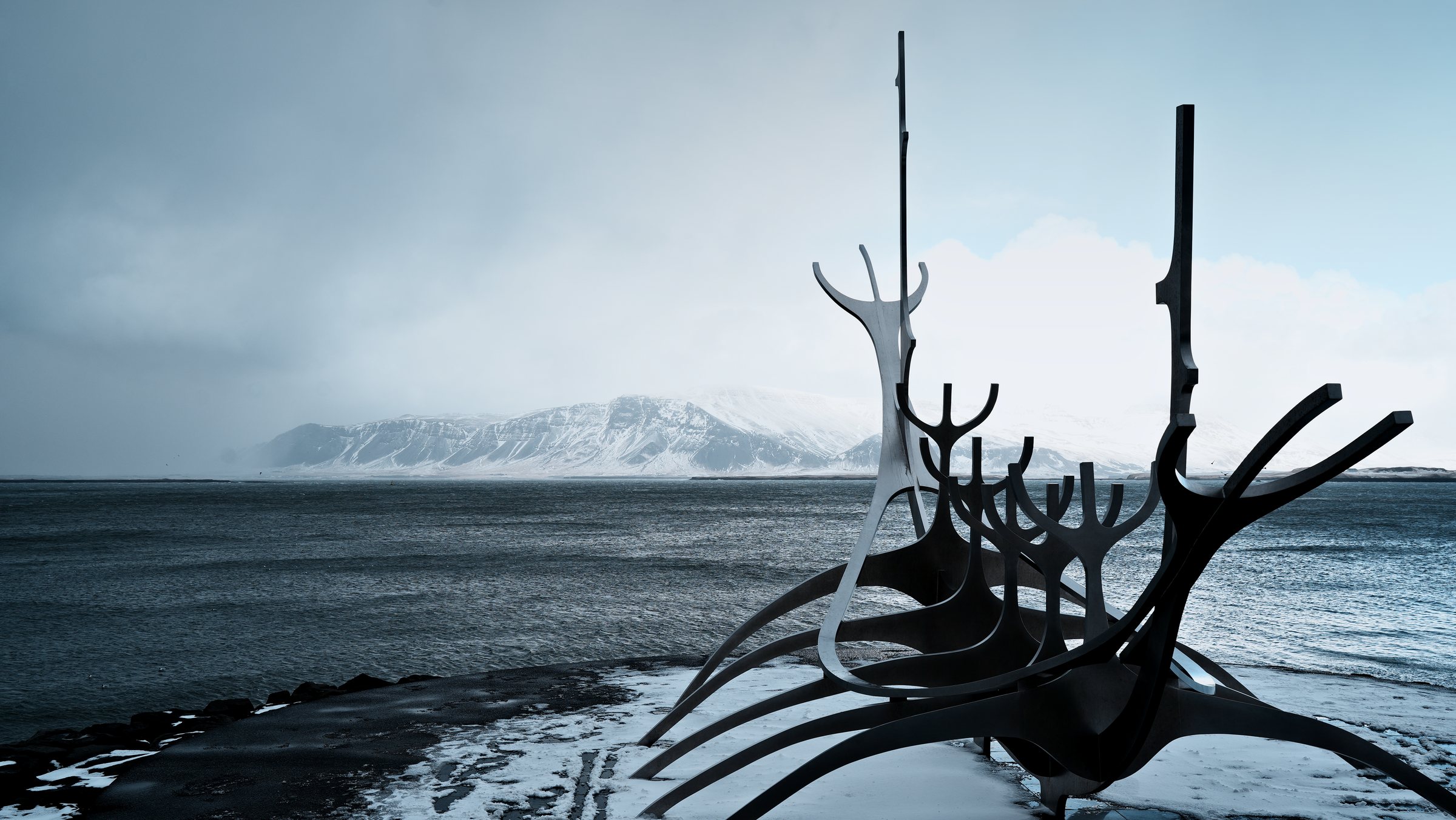 The Sun Voyager steel sculpture, close and low, its curved ribs and masts crossing the mountains across the bay.