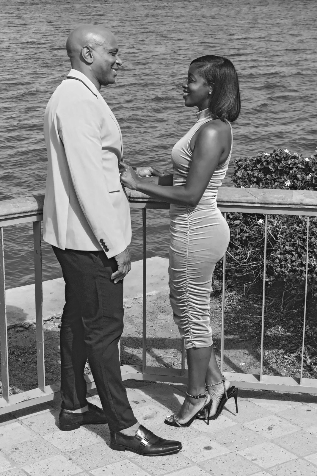 Black and white: couple holding hands at the railing, facing each other