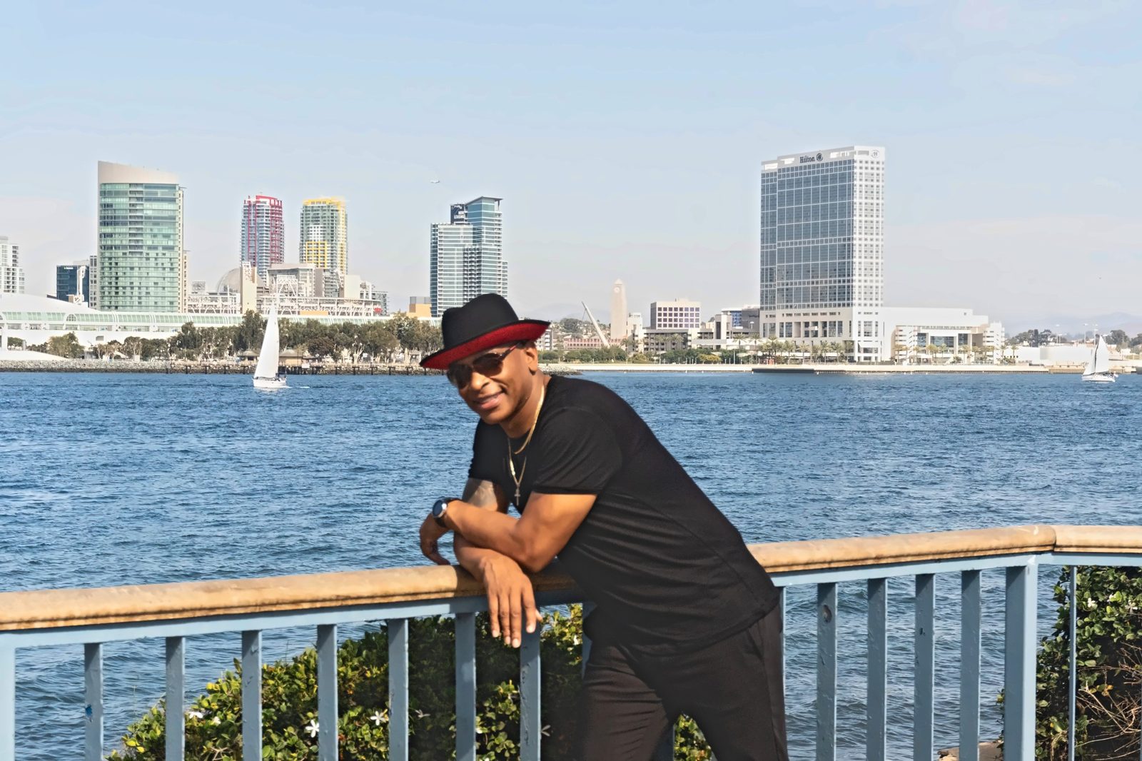 Man in a black hat with red band leaning on the railing