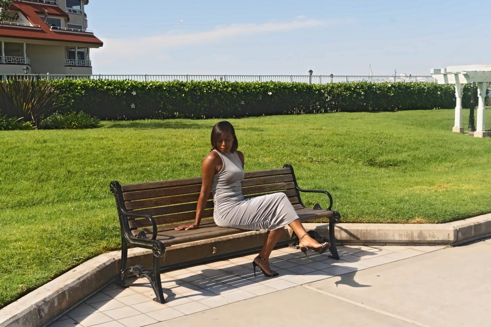 Woman in a silver dress seated on a wooden bench on the lawn